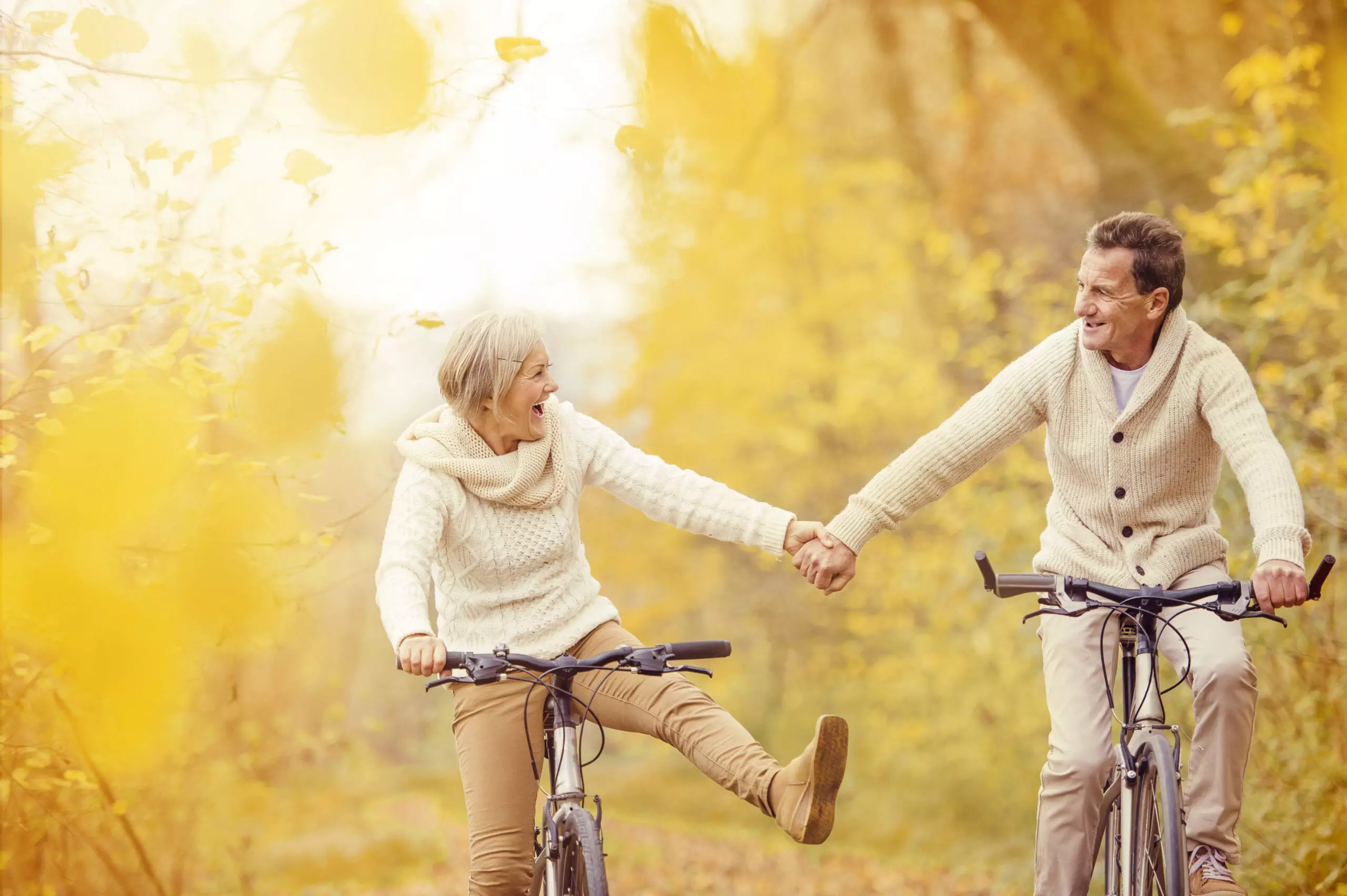 Couple biking and laughing in autumn scenery