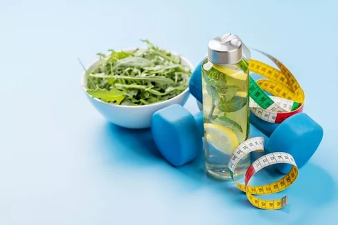 Healthy diet concept with salad, infused water, dumbbells.