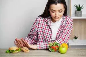Woman choosing salad over burger and cookies; Keto diet healthy